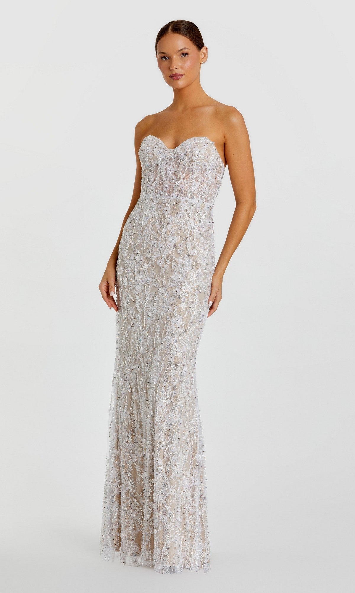An elegant woman stands against a plain white background, wearing the Mac Duggal 68893 long formal dress in Ivory Nude, which features intricate white lace detailing and delicate floral beadwork.